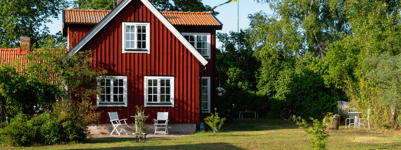 rott-hus-med-vita-knutar-och-vita-solstolar-pa-en-grasmatta